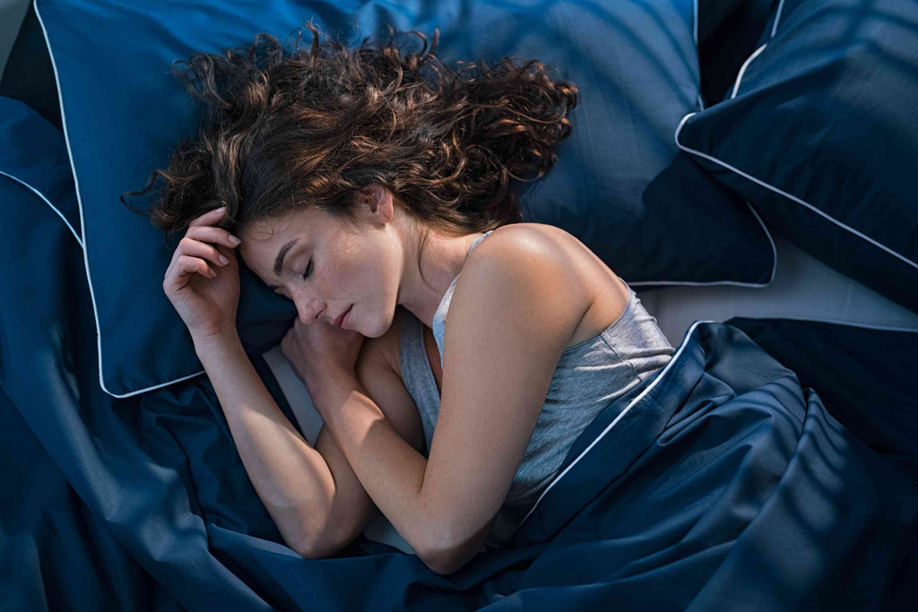 vrouw op bed onder deken